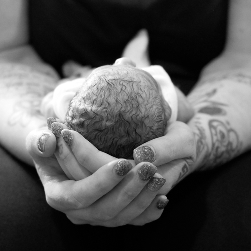 Close up of a parent holding their baby, cupping its head in their hands