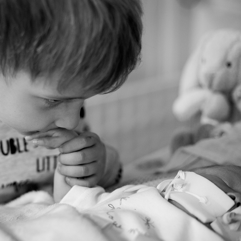 Boy holding and kissing a baby's hand