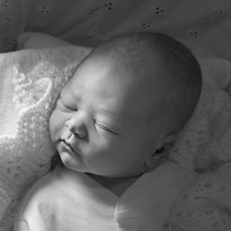 Dark monochrome image of a sleeping baby from above